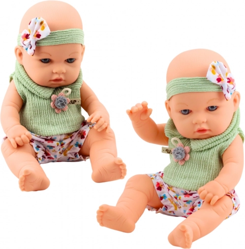 Babydukke i grønt outfit med blomstermønster og hårbånd med sløjfe