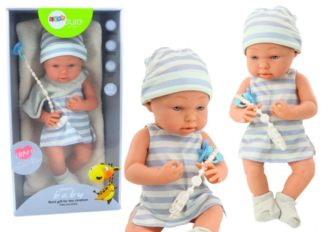 Babydukke i hvid-blåt tøj med hue og sut